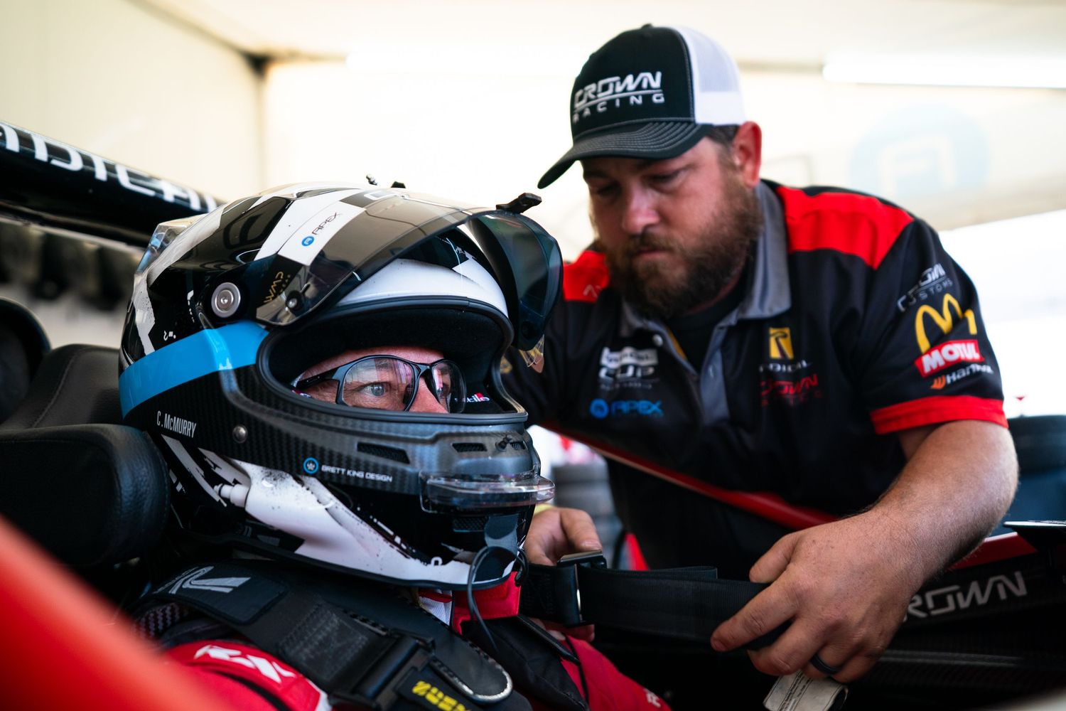 Technical crew working on race car components in professional pit garage.