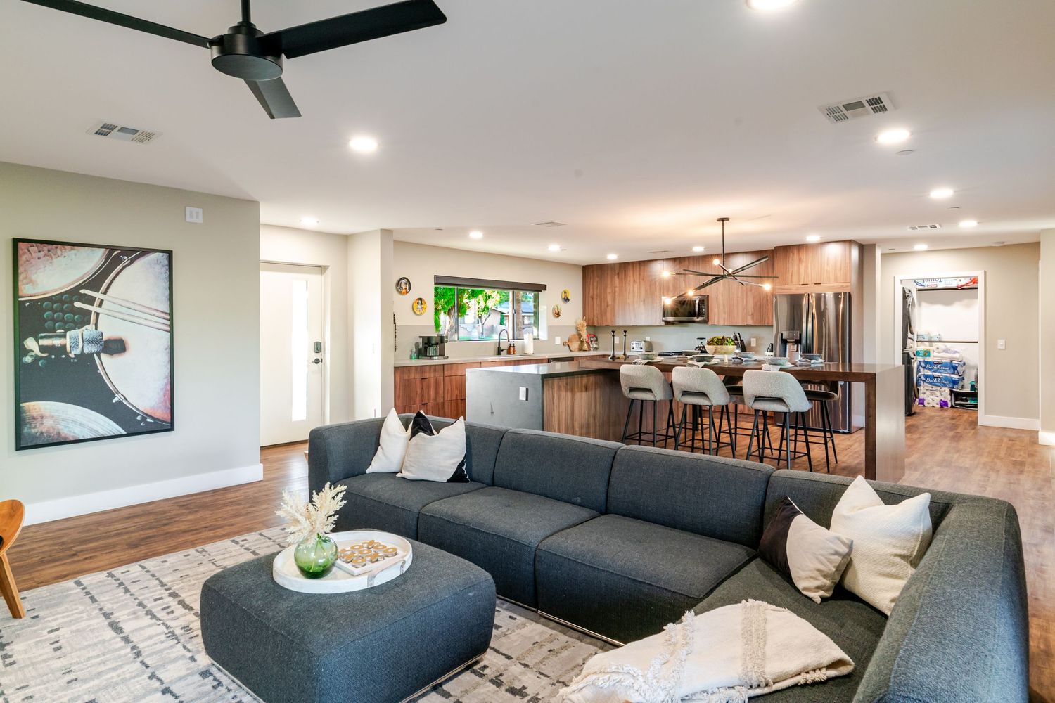 Modern living room featuring grey sectional sofa, ceiling fan, and contemporary decor in an open floor plan.