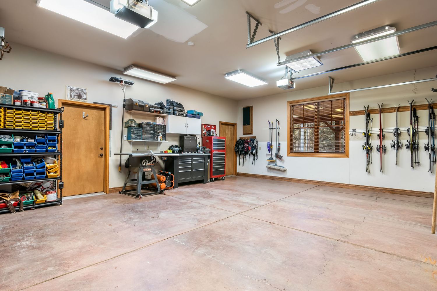 Panoramic view of a clean, well-lit garage workshop with organized storage shelves and wooden cabinets along the walls.