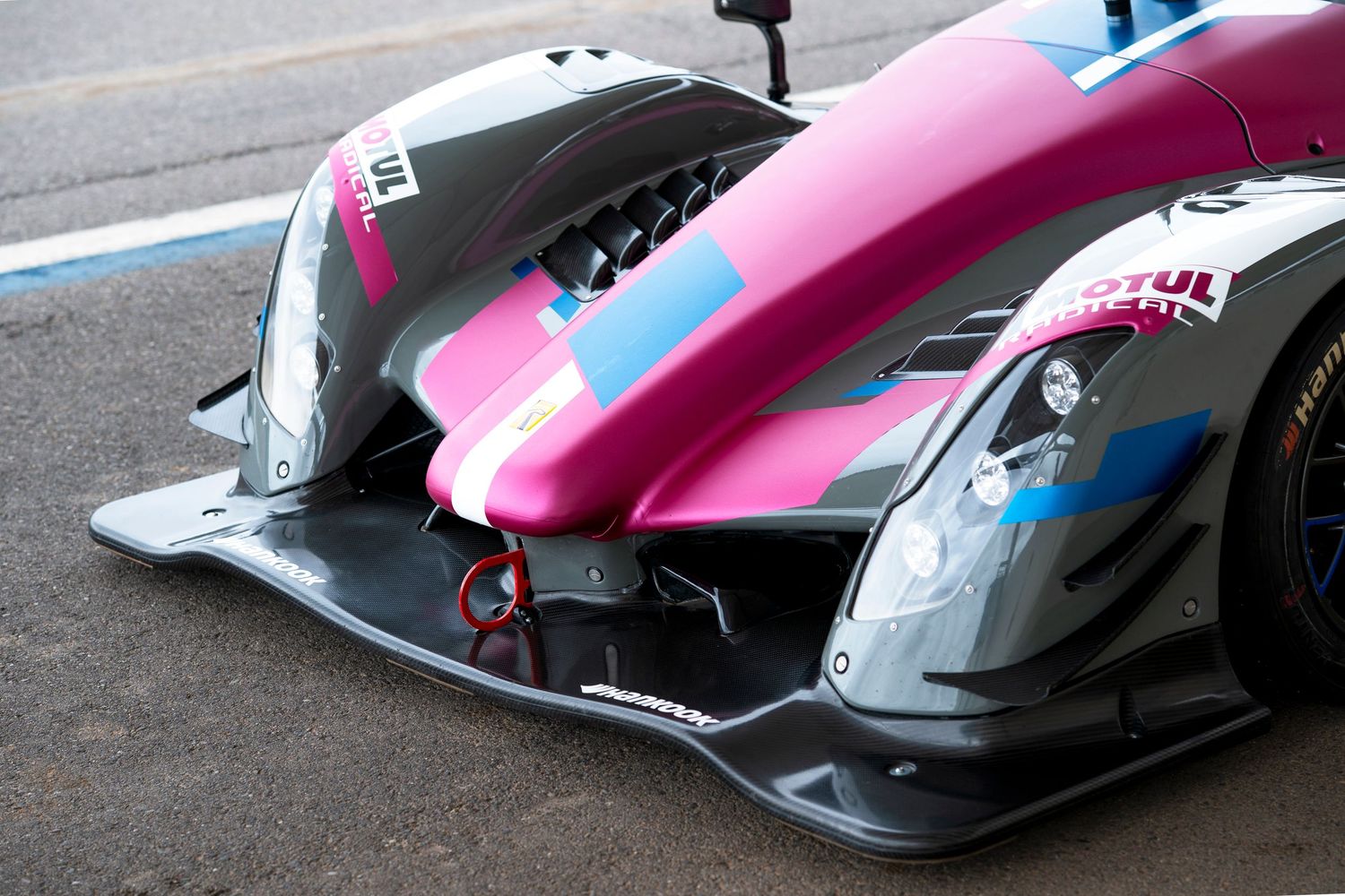Close-up detail of a pink and silver racing car's aerodynamic front wing and bodywork.