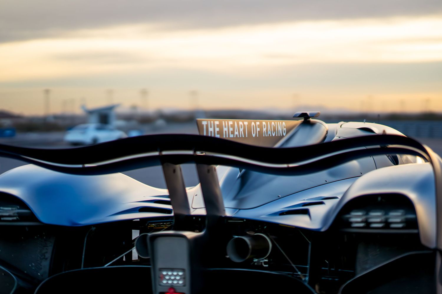 Detail shot of racing car's aerodynamic bodywork and rear wing at sunset.