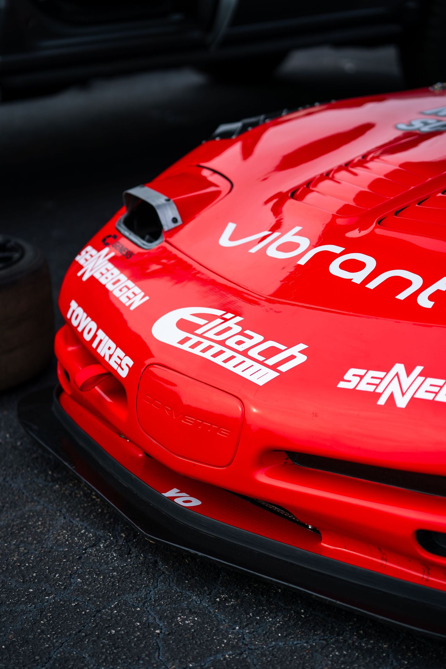 Close-up of a bright red Mazda RX-7 race car with Vibrant, Eibach, and Toyo Tires sponsor decals.