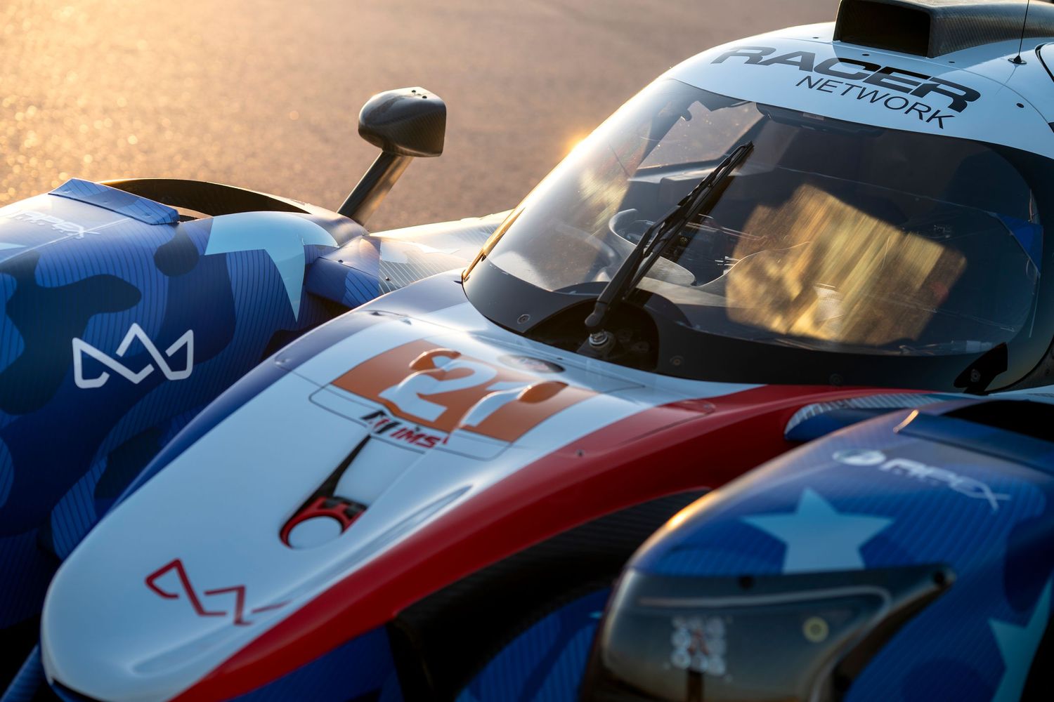 Close-up view of a blue and white racing car cockpit with red accents at sunset.