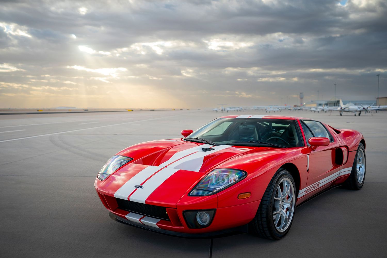 Modern Ford GT in red and white photographed at sunset on empty tarmac.