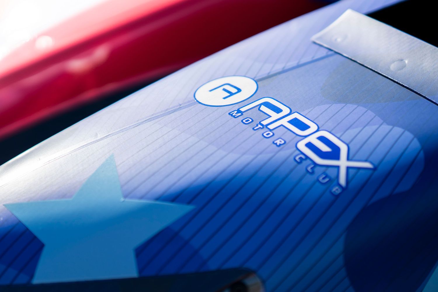 Detail shot of racing car bodywork showing gradients from red to blue coloring.