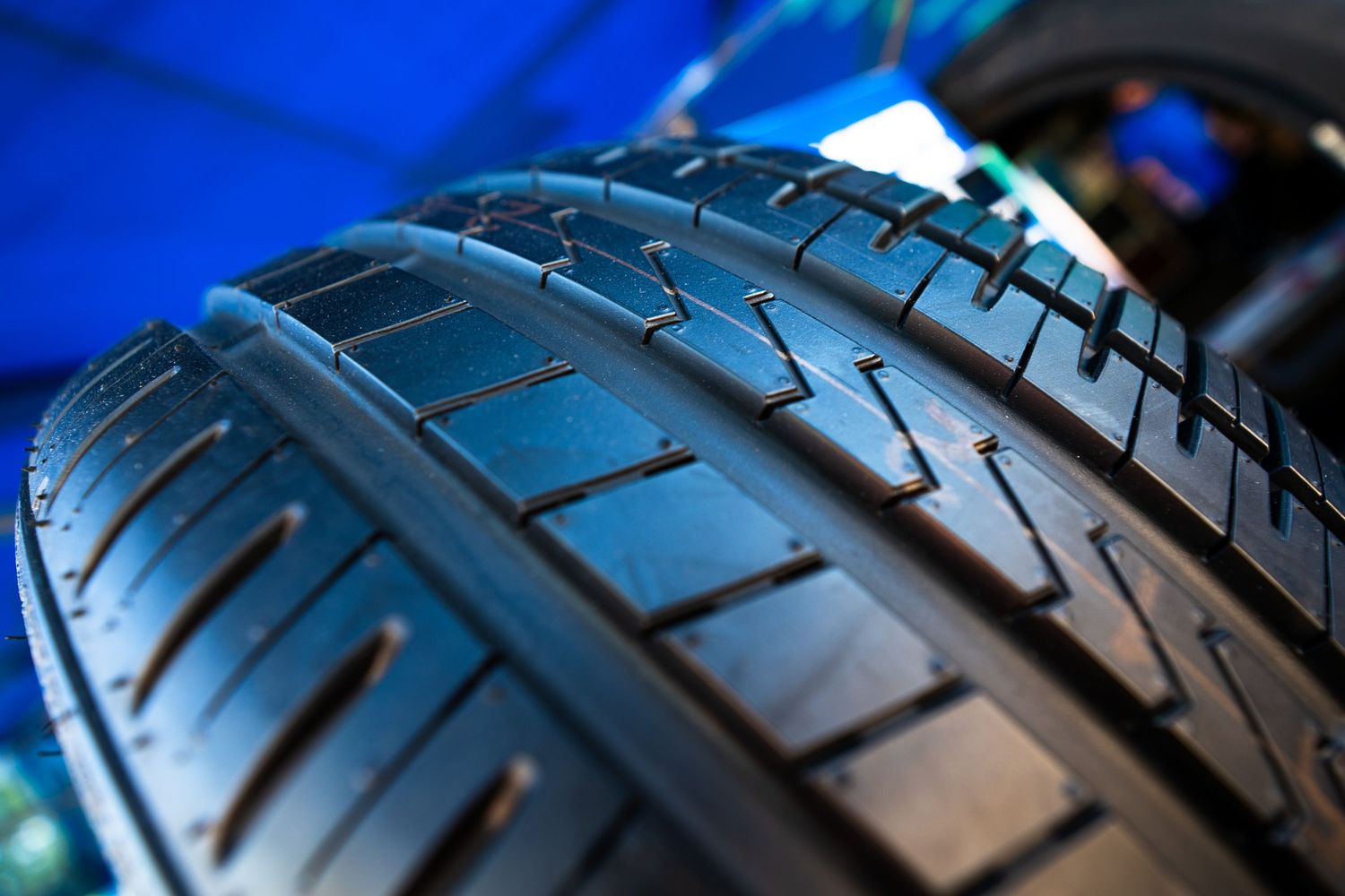 Close-up of black performance tire tread with blue background at motorsport event.