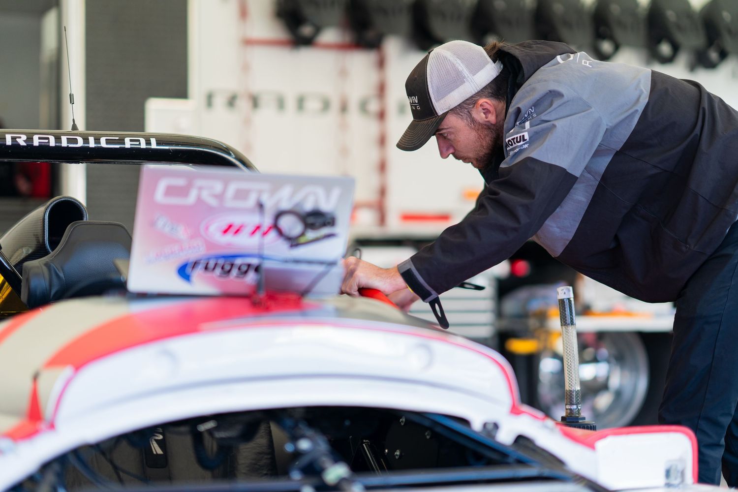 Close-up view of automotive maintenance work being performed underneath a racing vehicle.
