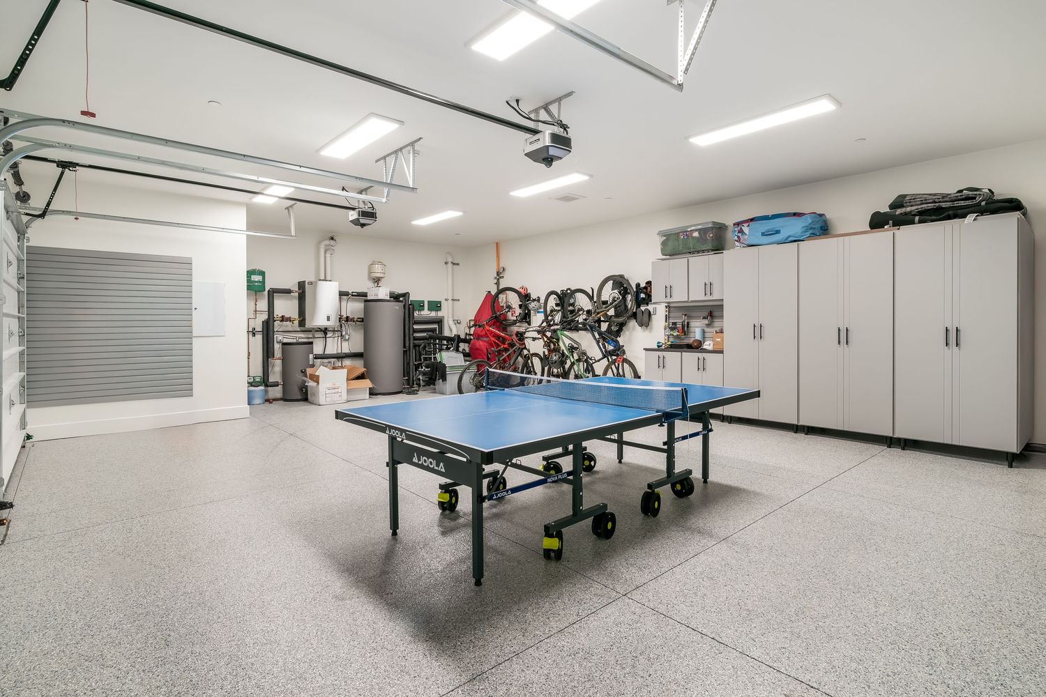 Clean white garage interior with epoxy floors and storage cabinets along the walls.