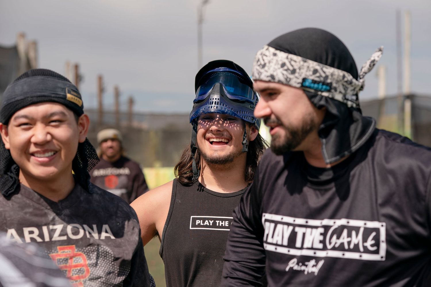 Three paintball teammates sharing a lighthearted moment between games.