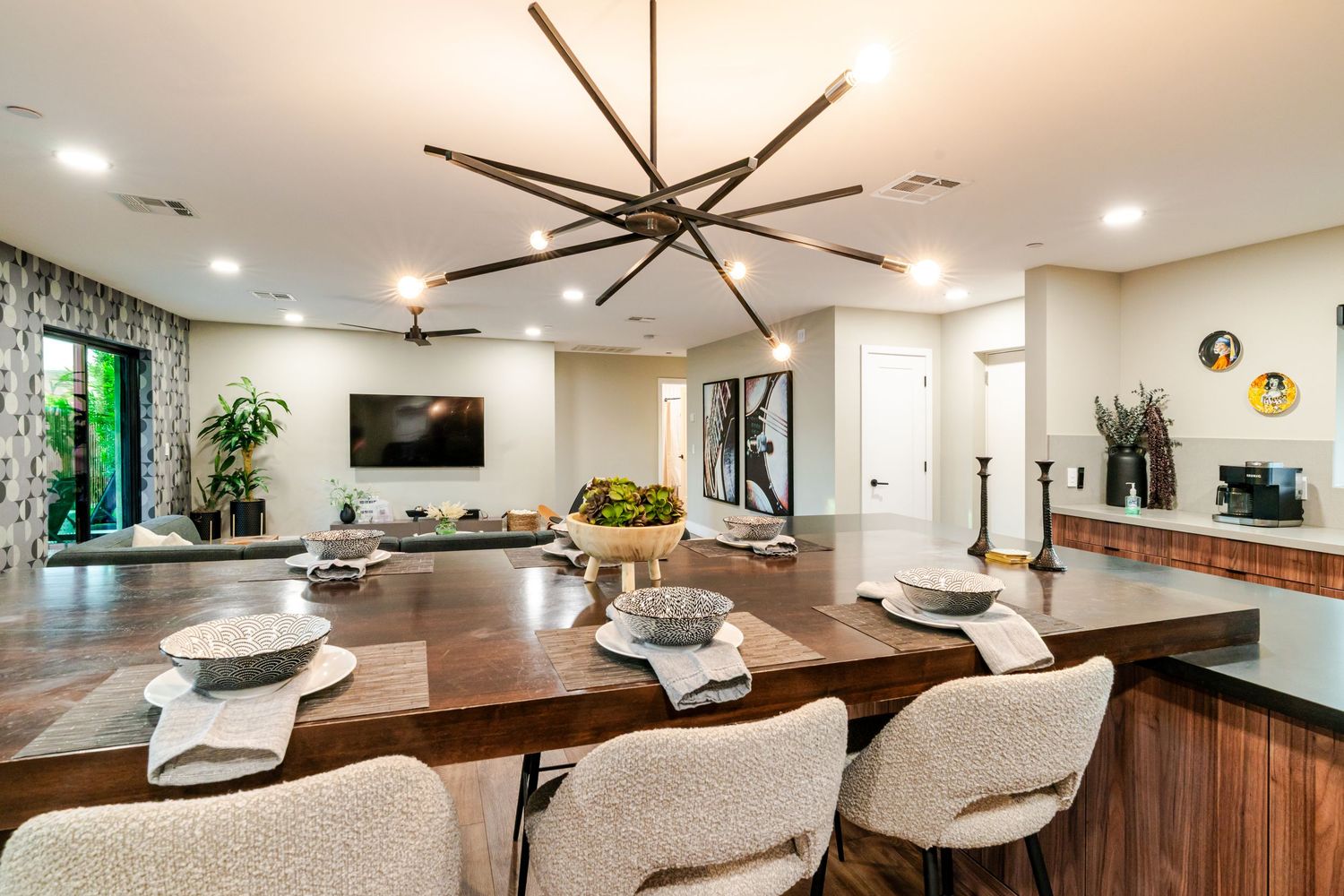 Contemporary dining area with statement chandelier, upholstered chairs, and wooden table in neutral tones.