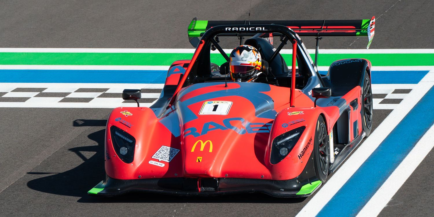 Bright red prototype race car with McDonald's livery on a racing circuit with green and blue track markings.