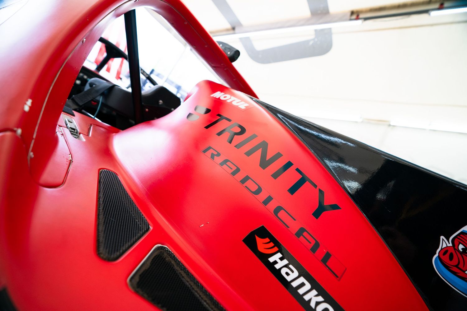 Red Trinity racing car detail showing branding and technical components.