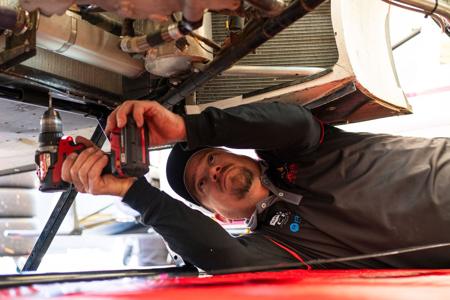 Mechanic working underneath a vehicle on an automotive lift during maintenance service.