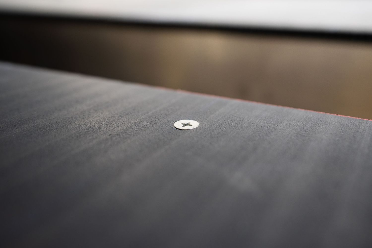 Macro shot of a small circular metal component mounted on a textured dark surface.