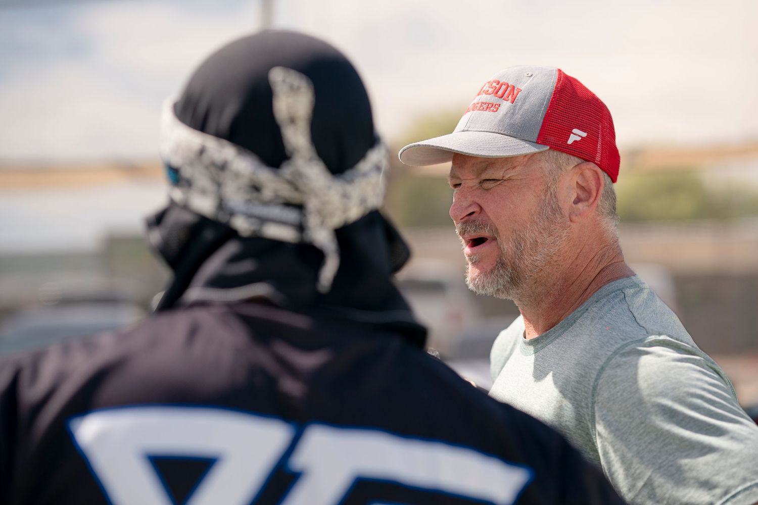 Players engaged in conversation during paintball tournament break.