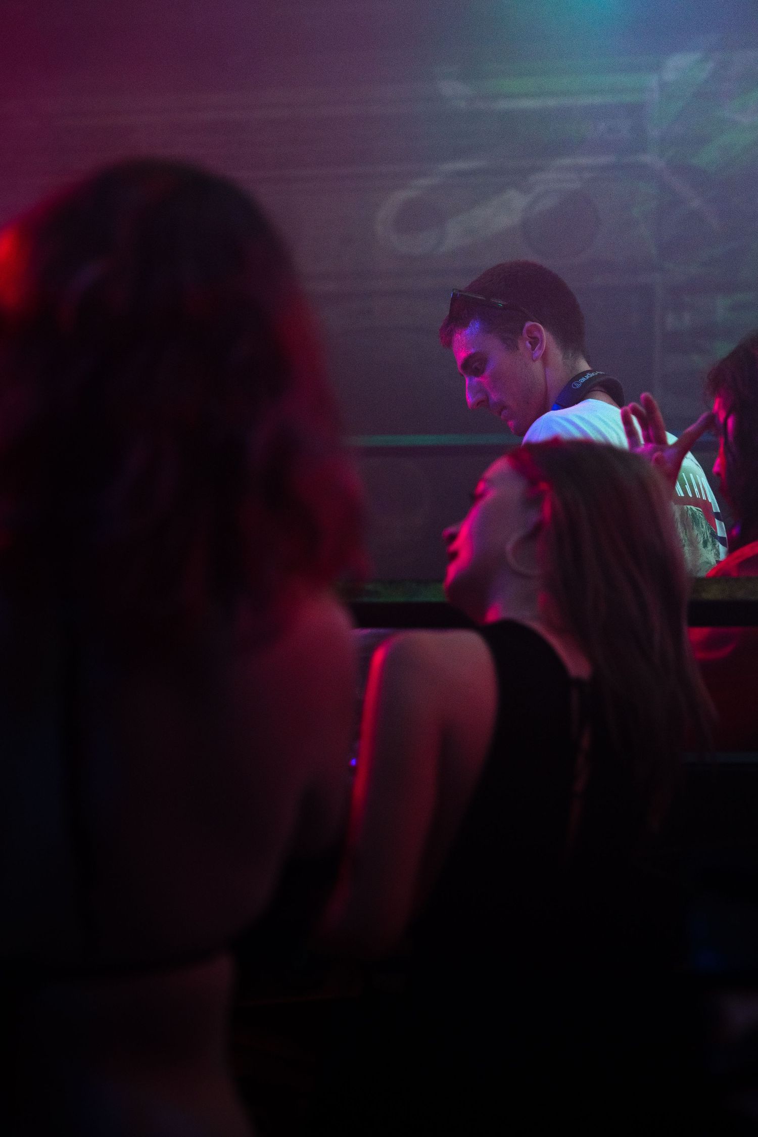 Crowd silhouettes dancing in a dark nightclub with red and purple lighting effects.