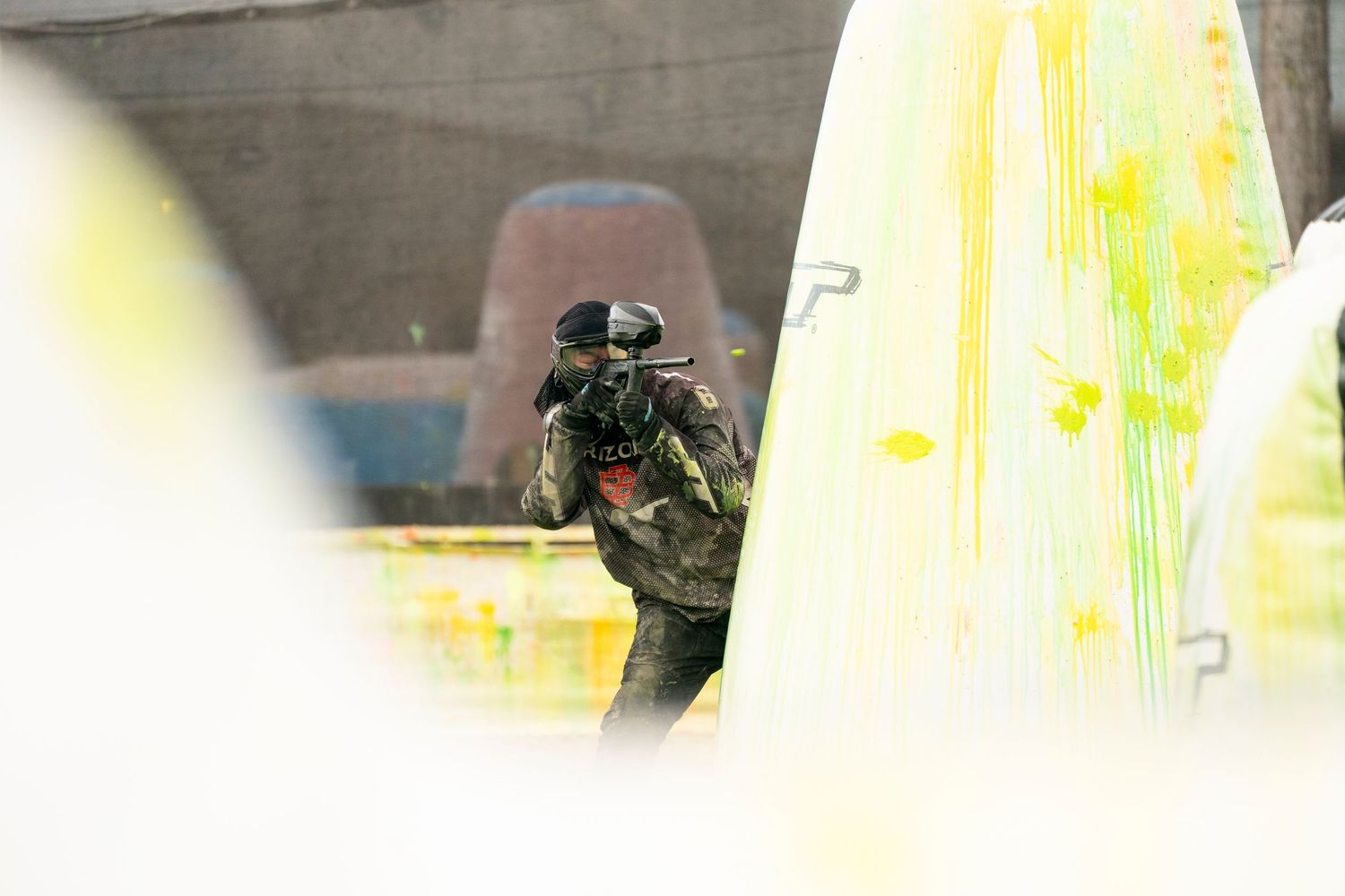 Player moves stealthily between inflatable bunkers during paintball match.