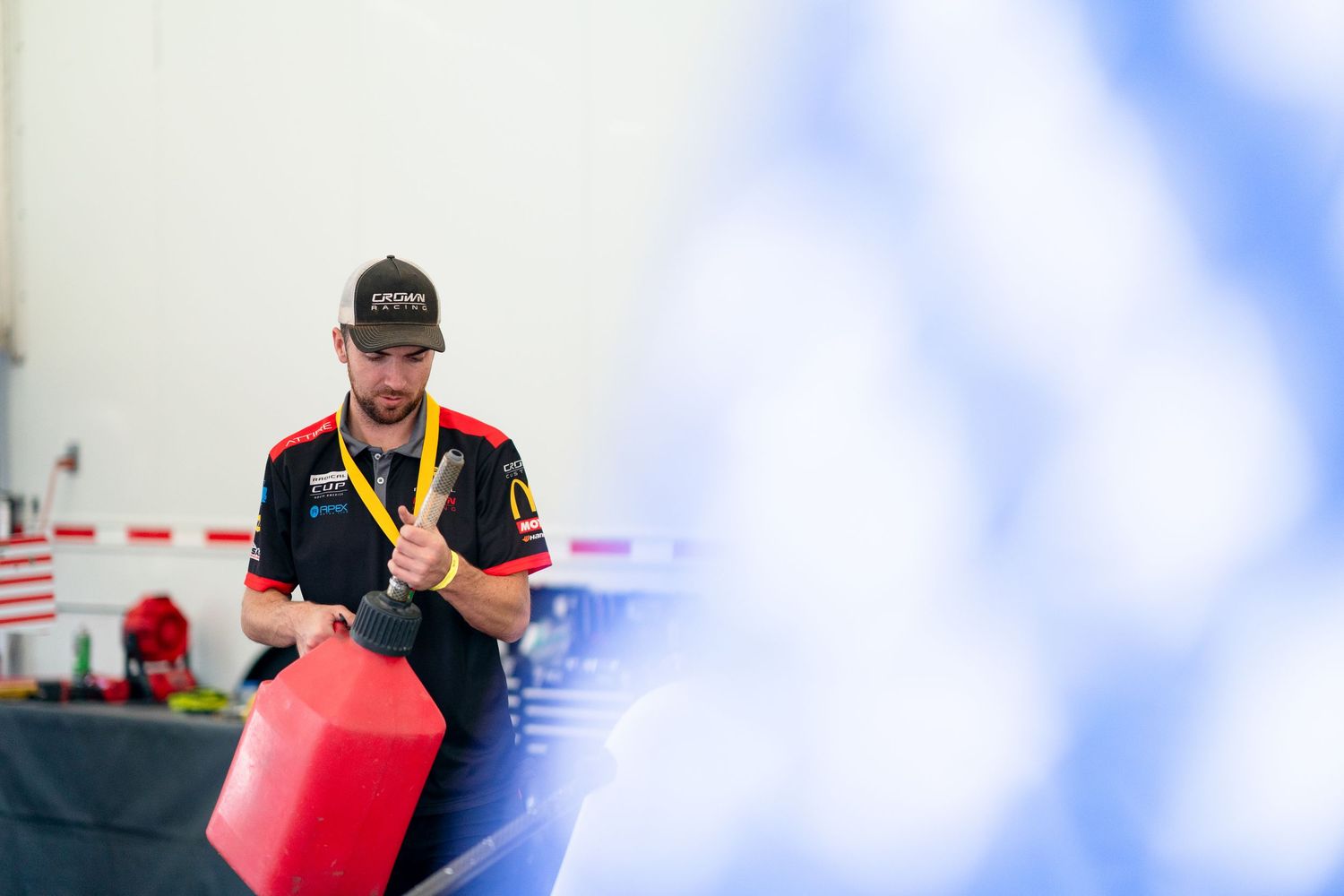 Racing team crew member working on vehicle maintenance in the garage.