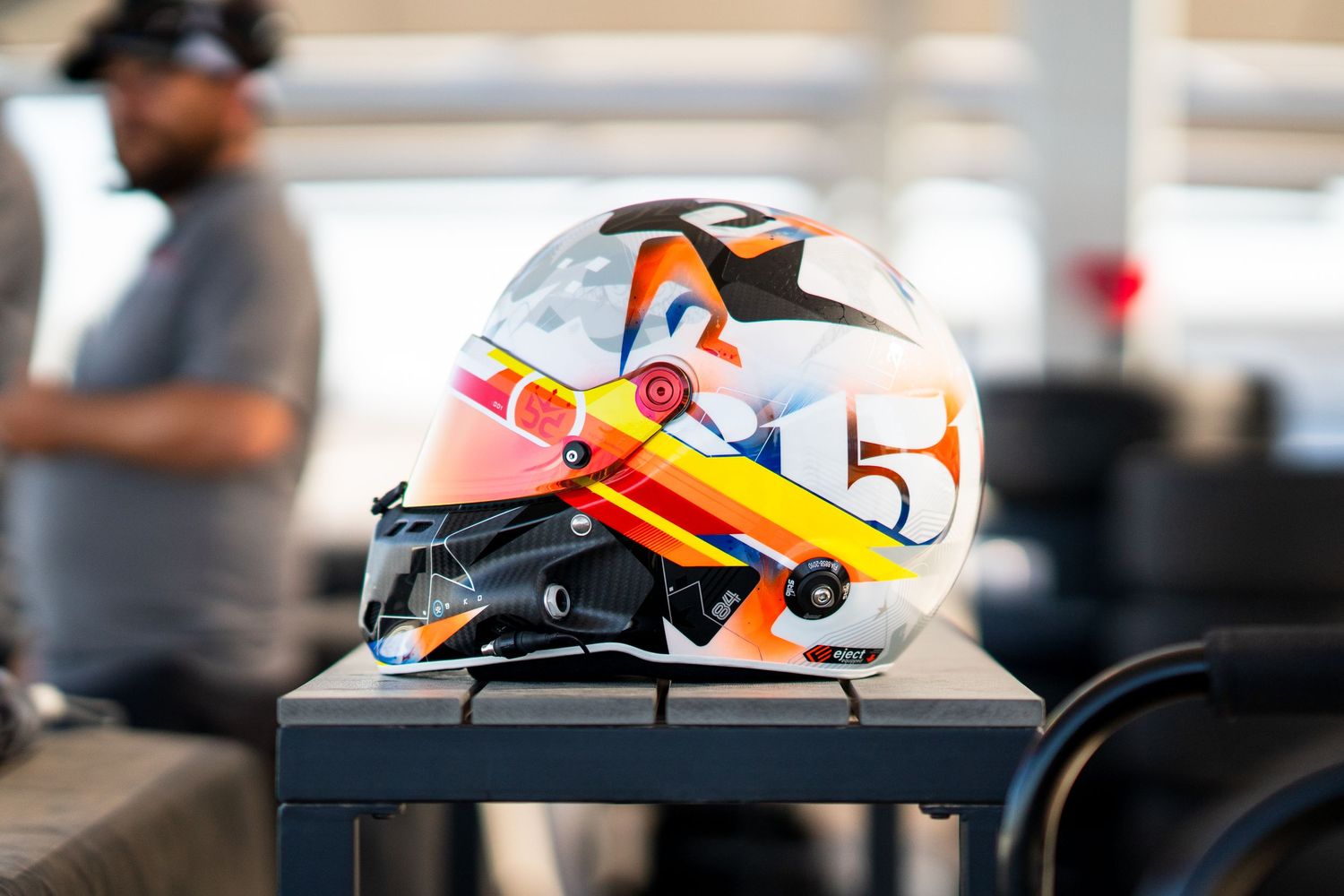 Racing helmet detail showing orange and white design elements in car cockpit.