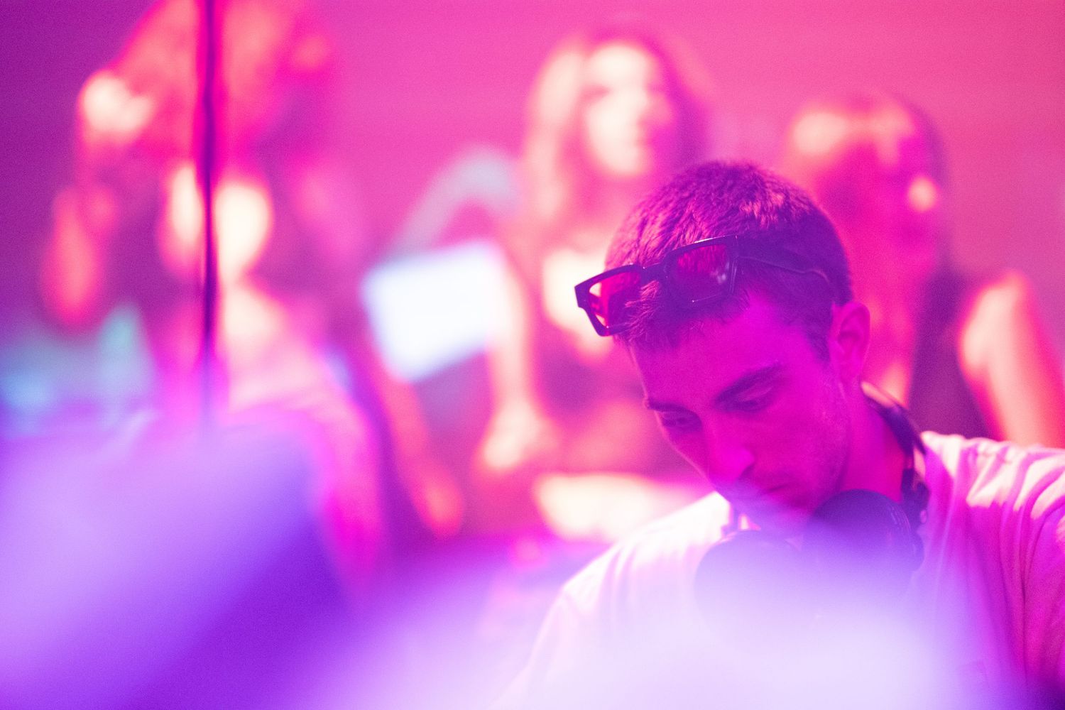 Abstract blurred nightclub scene bathed in pink and purple lighting creating a dreamy atmosphere.