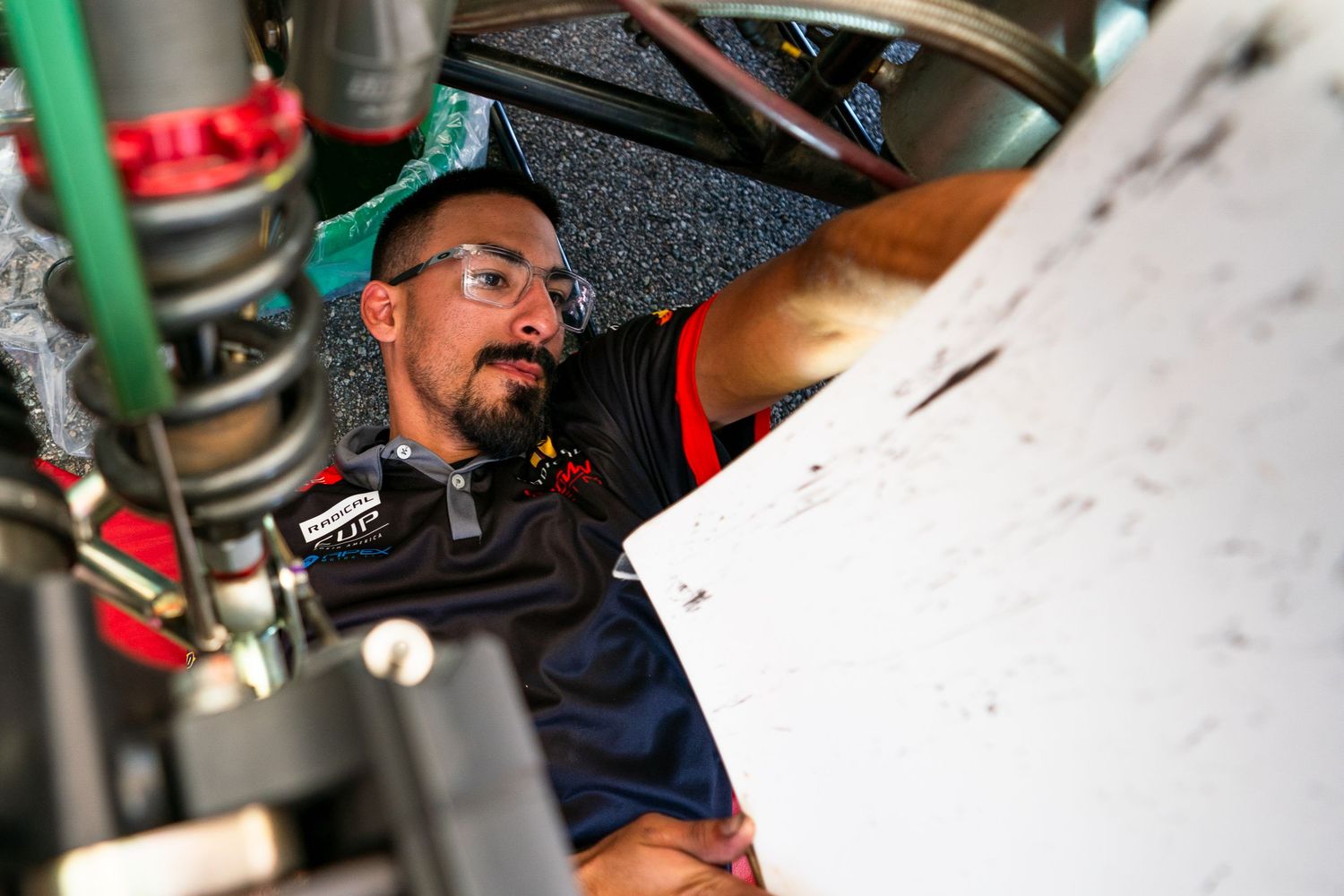 Detailed view of racing car maintenance being performed in a professional garage setting.