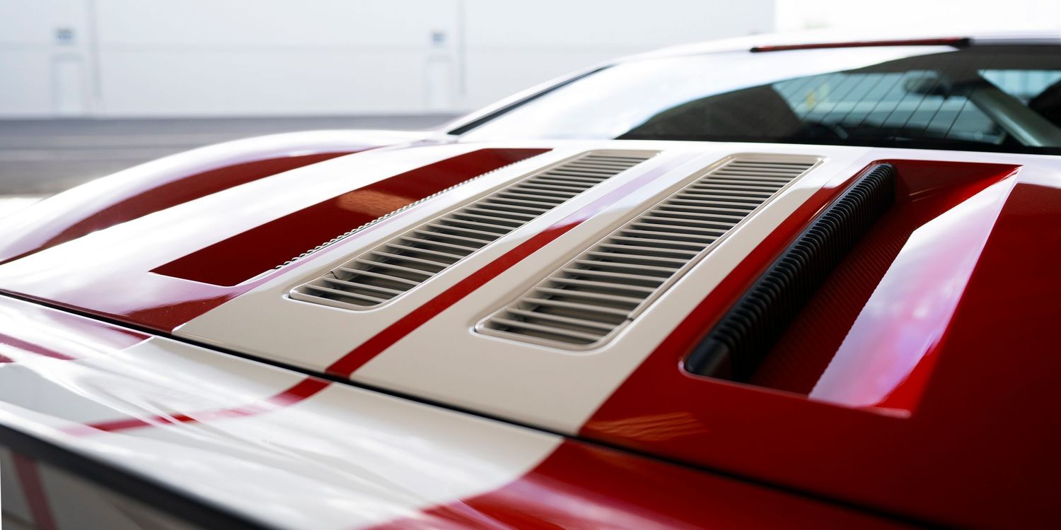 Air vents and racing stripes on the hood of a red sports car.