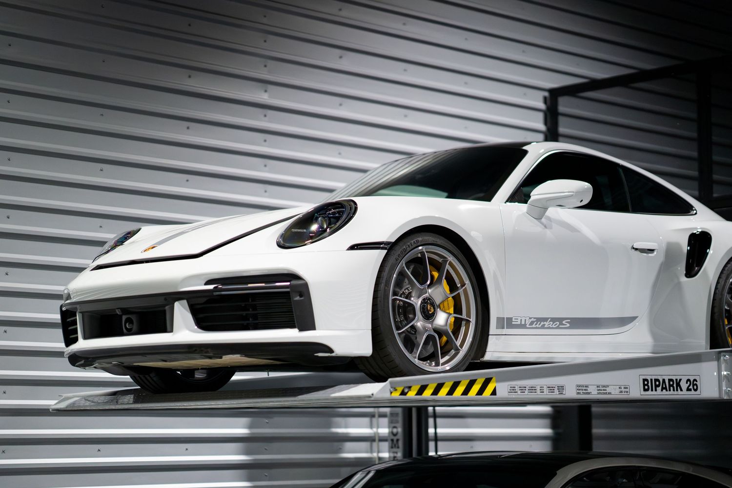 Sleek white sports car displayed in a modern showroom with dramatic lighting and metallic accents.
