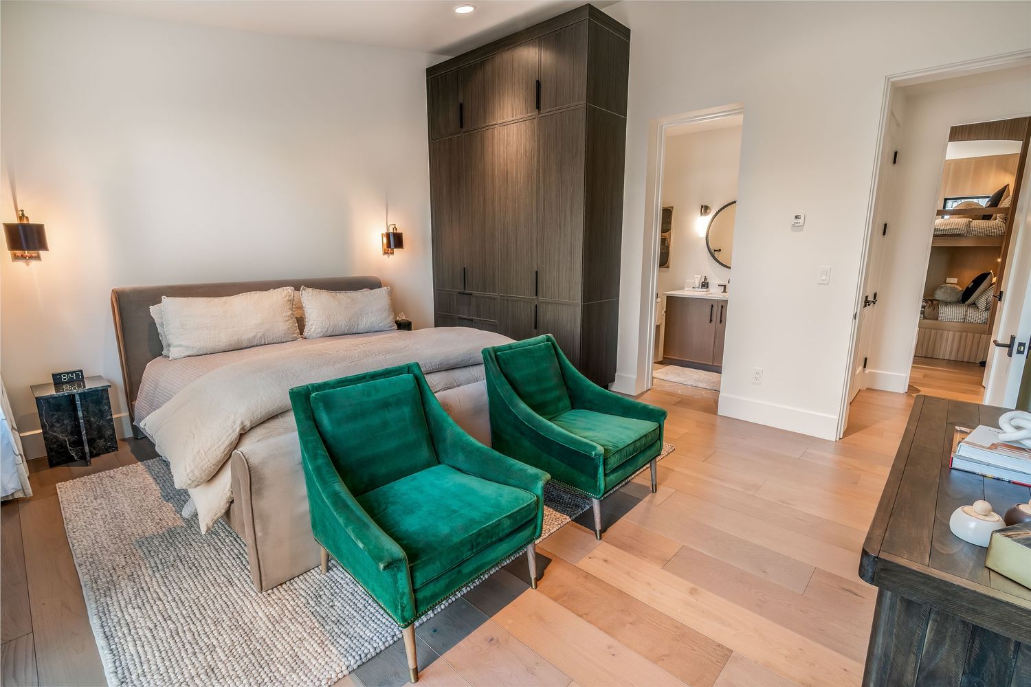 Modern apartment interior with emerald green velvet sofa and hardwood floors in an open concept living space.