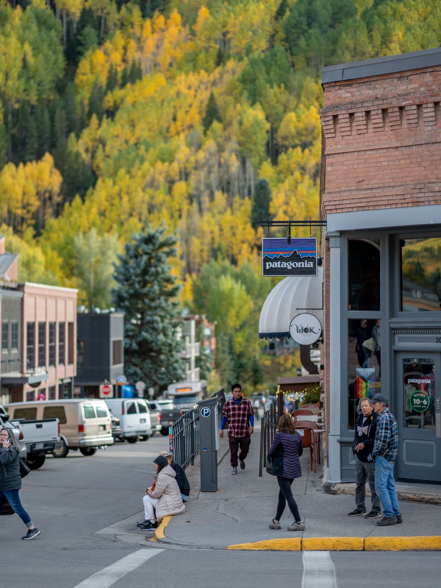 Small mountain town street with historic buildings and autumn foliage in background.