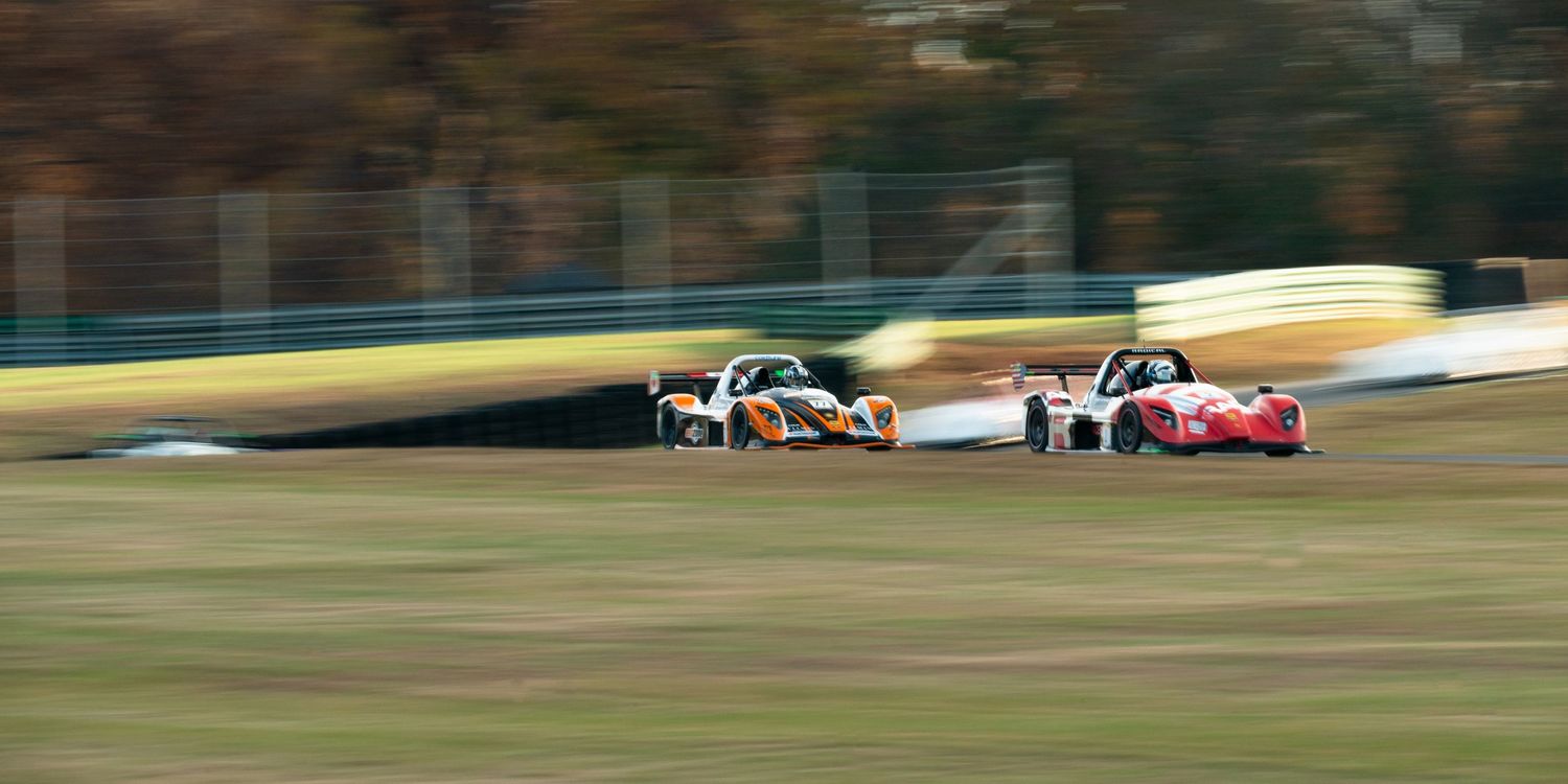 Motion-blurred racing action shot of cars competing on professional circuit.