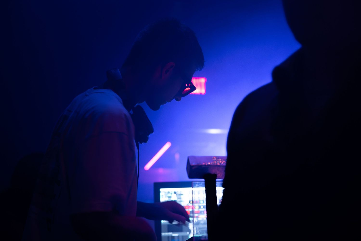 Silhouetted figures dance under dark blue lighting at a nightclub or concert venue.
