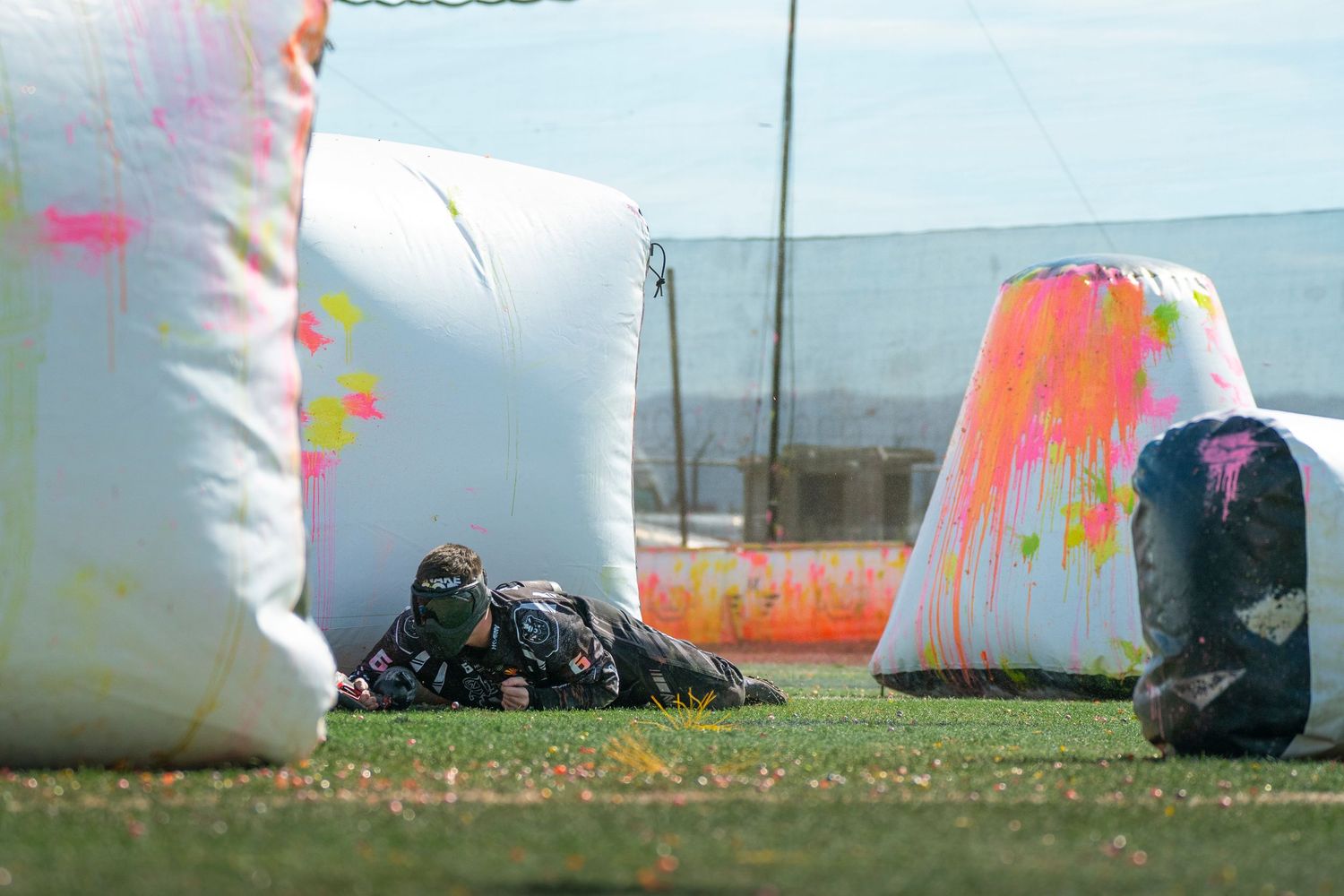 Paintball bunkers and inflatable barriers set up on a grassy field during a game.