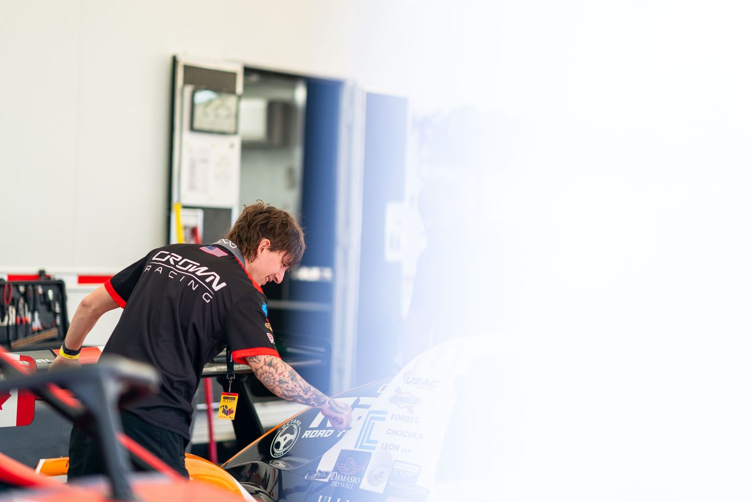 Professional racing team members collaborating in a bright indoor workspace.