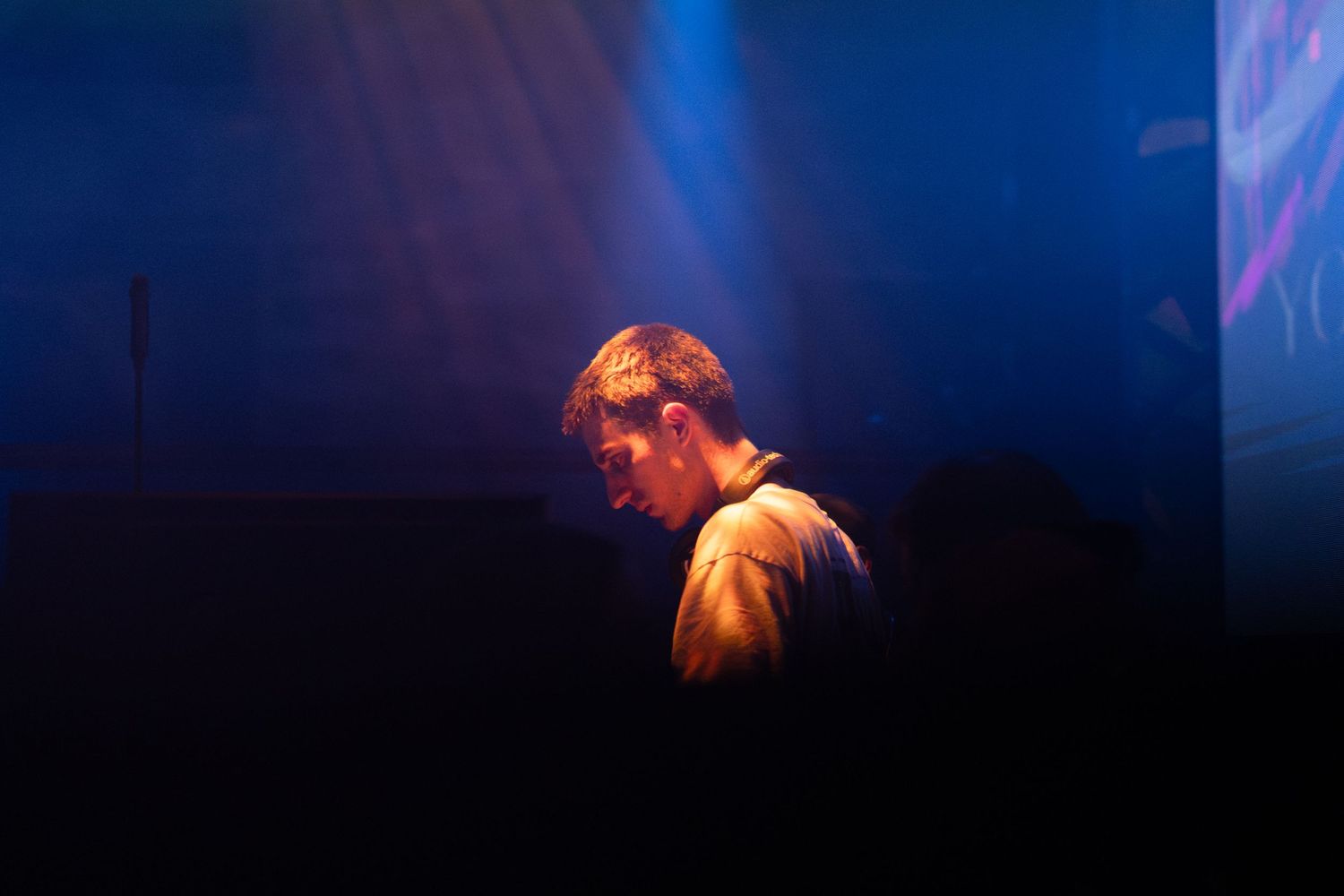 A concert performer silhouetted against dramatic blue stage lighting during a live music performance.