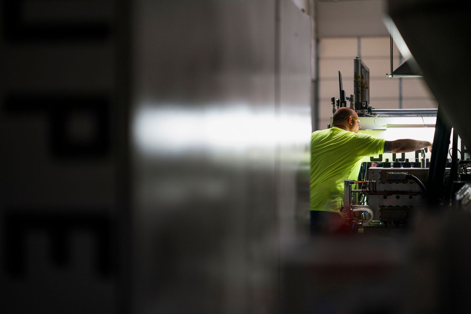 Blurred industrial workspace with machinery and bright lighting in background.