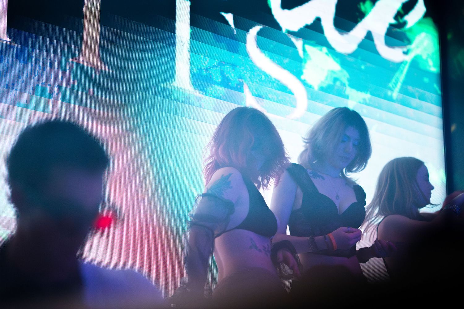 Silhouetted crowd dancing at a nightclub with blue lighting and atmospheric effects creating an energetic party atmosphere.