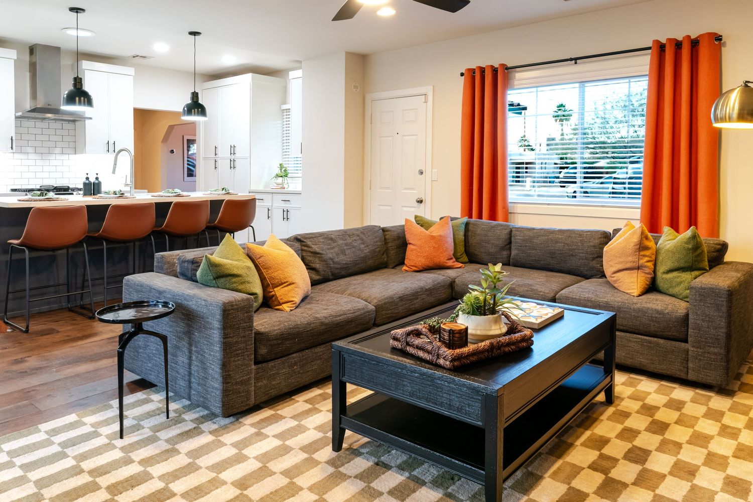 Contemporary living room with gray sectional sofa, orange accent pillows and geometric area rug.