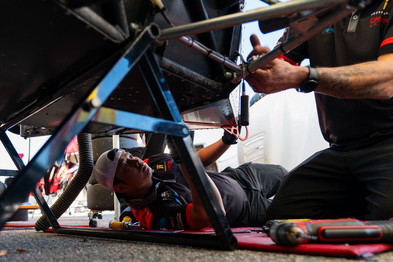 Mechanic hands working on motorcycle maintenance with tools and parts spread across a workbench.