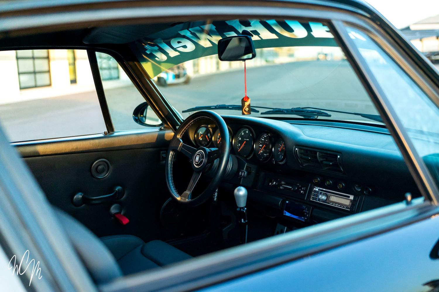 Interior view of a vintage car dashboard showing classic analog gauges and steering wheel through the windshield.