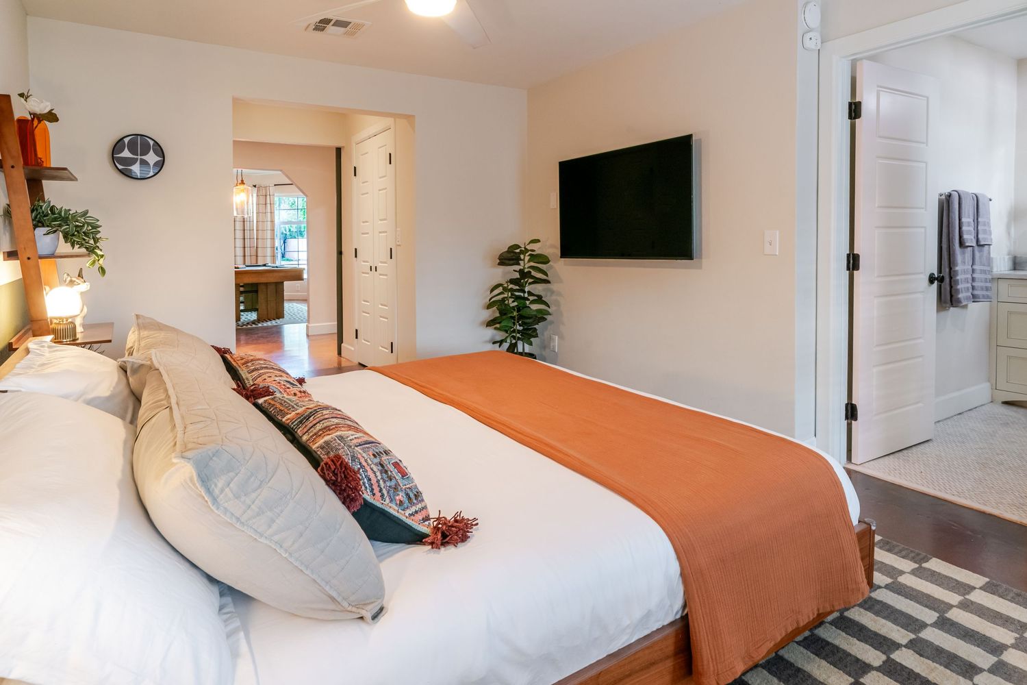 Modern bedroom interior with white bedding and orange accent wall showing multiple angles.