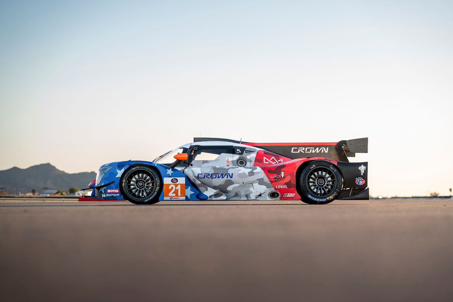 Racing prototypes lined up on track showing competitive motorsport scene at dusk.