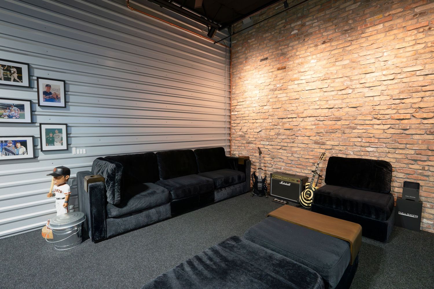 Modern entertainment space with black leather seating and framed artwork along white storage walls.
