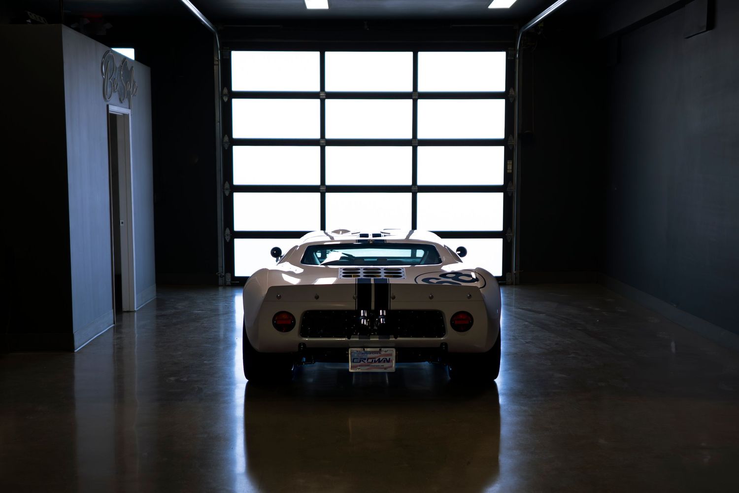 A dark interior hallway with bright windows and a car silhouette visible at the end of the corridor.