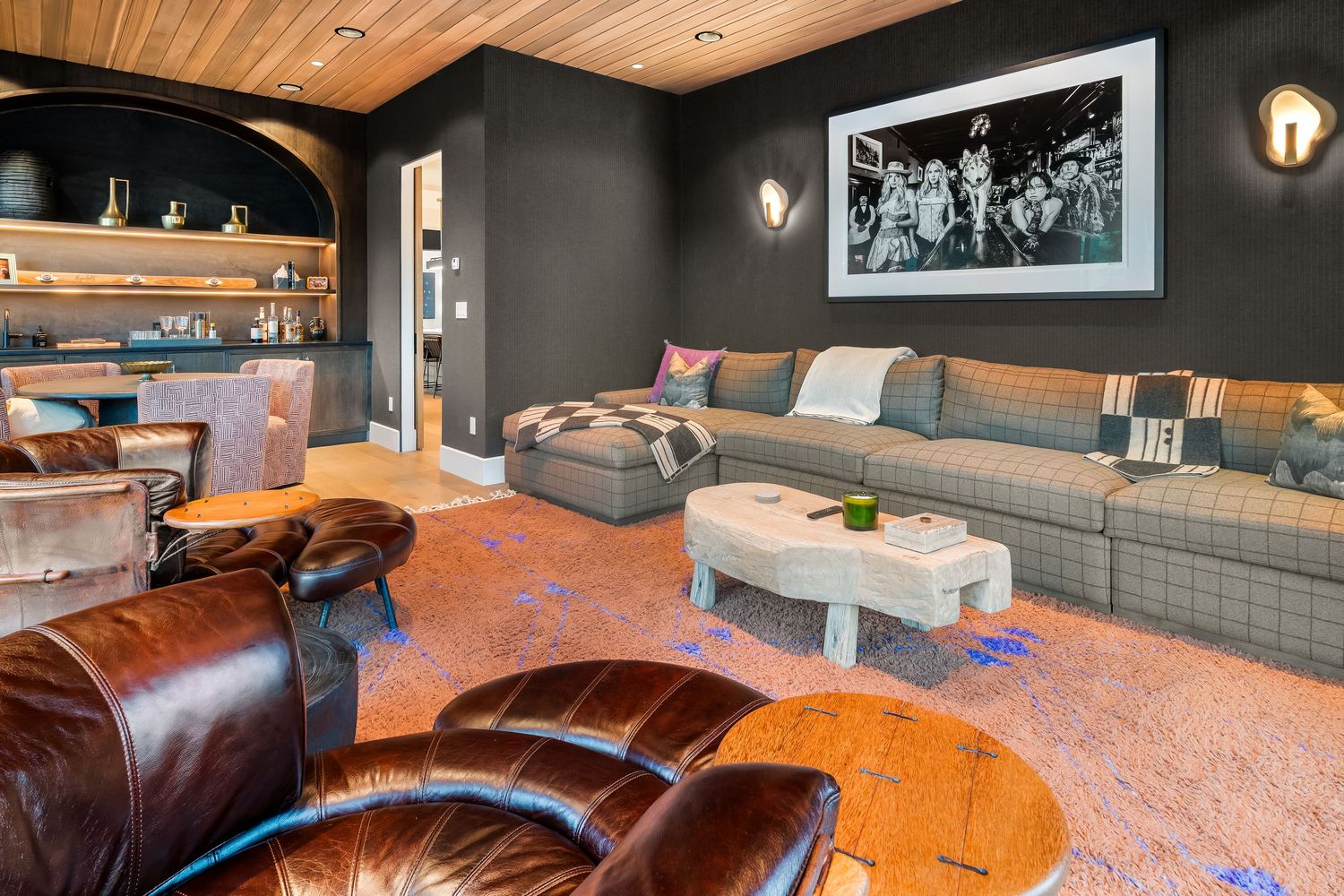 Cozy living room featuring leather furniture, wood ceiling, and dark walls with artistic accents.