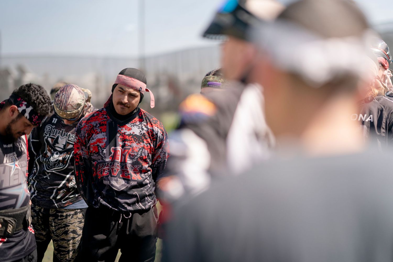 Group of players in paintball gear discussing strategy between games.