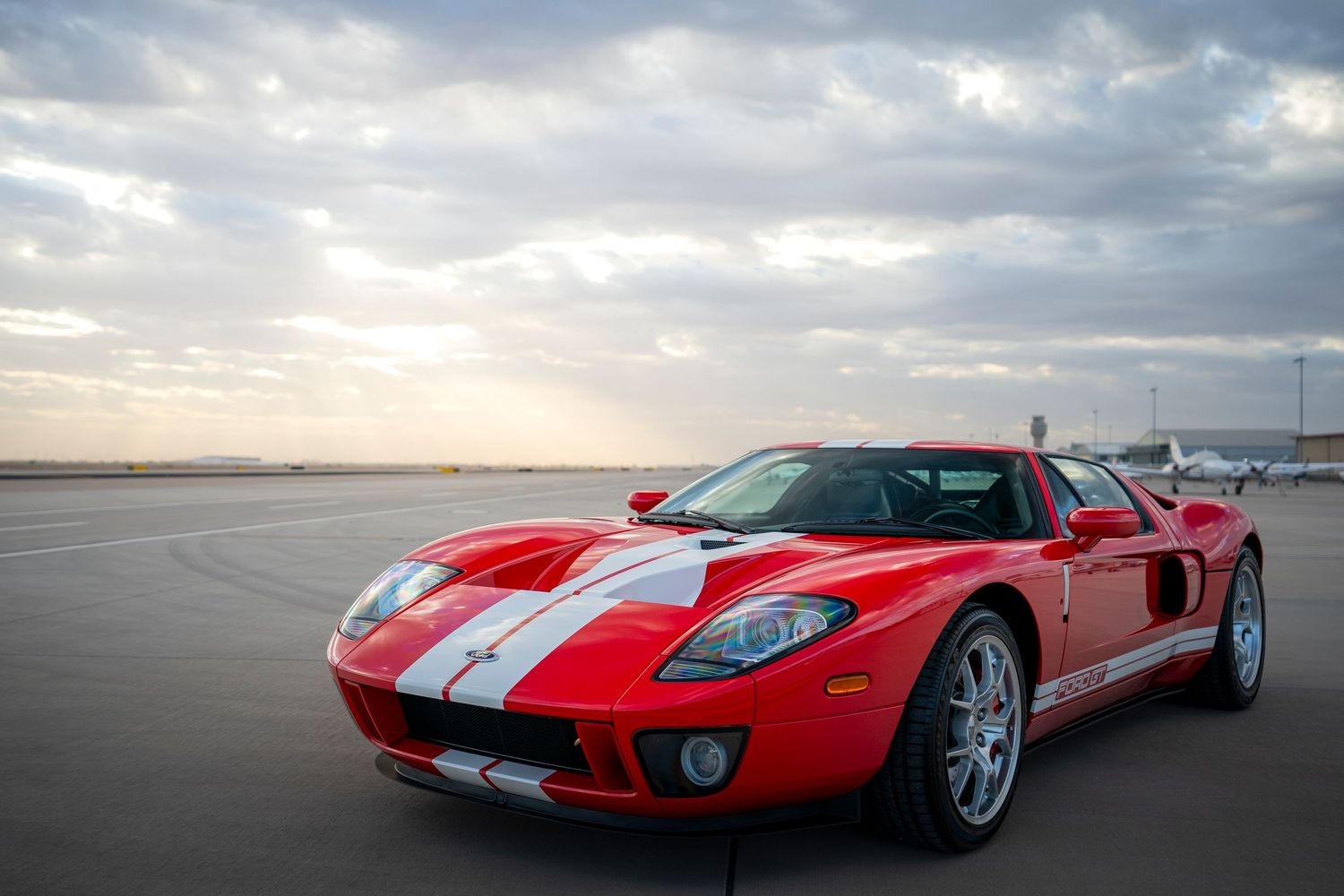 Red and white striped Ford GT photographed at sunset on empty runway.