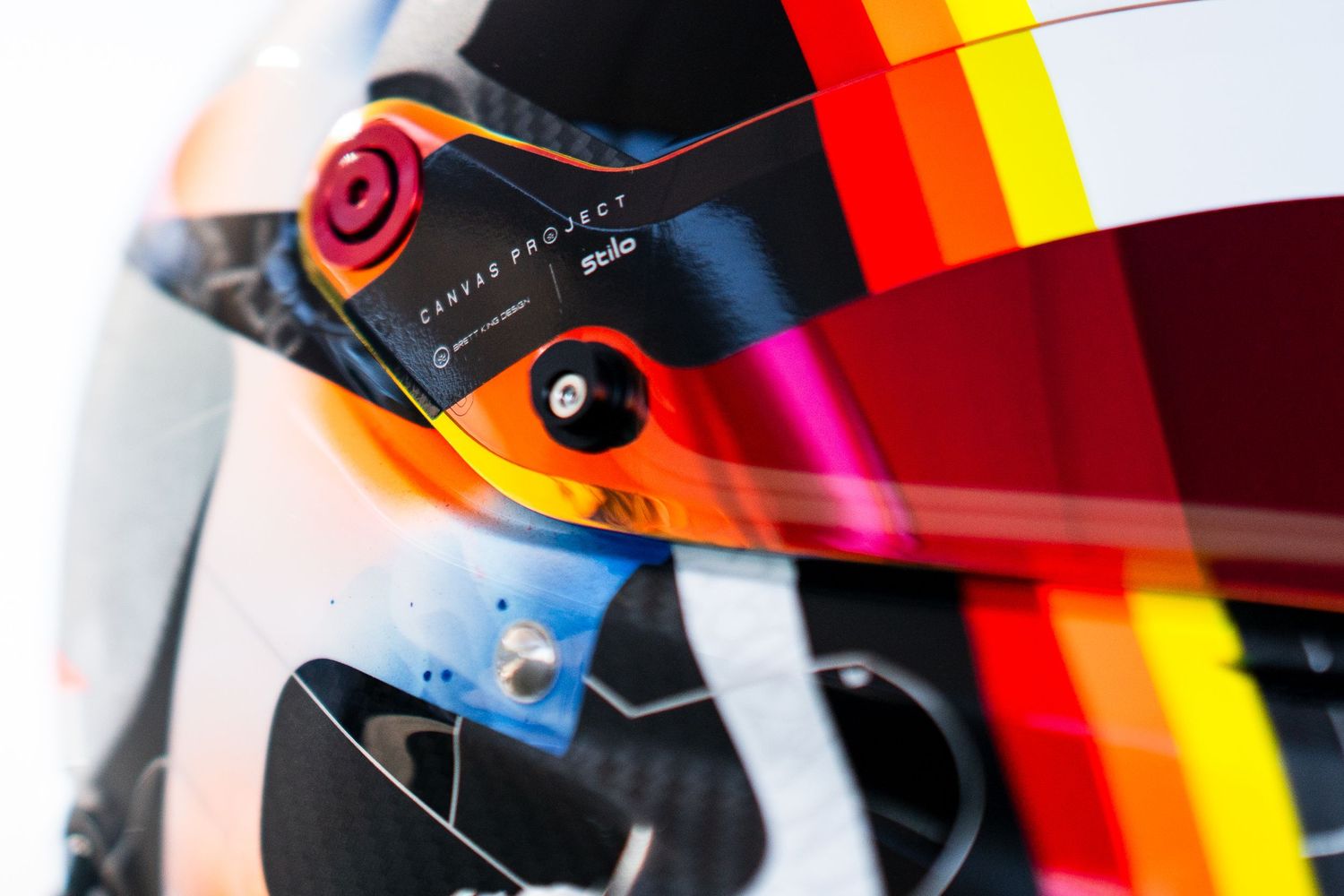 Close-up detail of a racing helmet visor with colorful stripes and reflective surface.