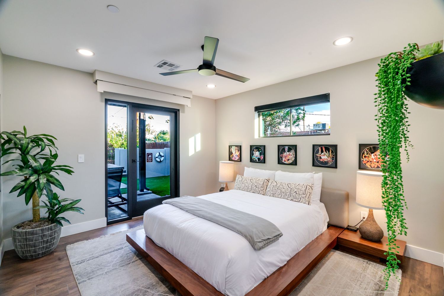 Bright bedroom with platform bed, indoor plants, and glass doors leading to outdoor space.