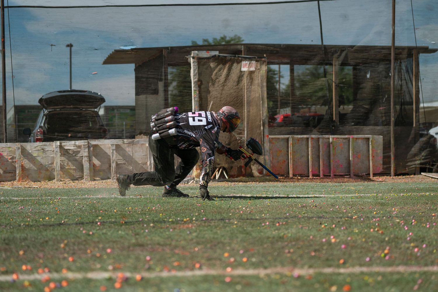 Paintball competitor diving for cover on grass field during match.