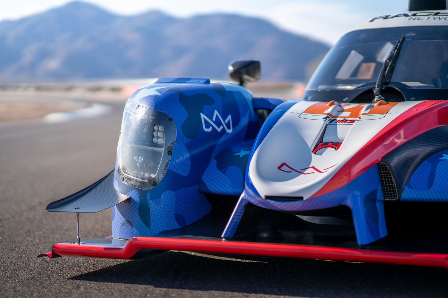 Front view of patriotic themed LMP2 race car nose with mountain backdrop.